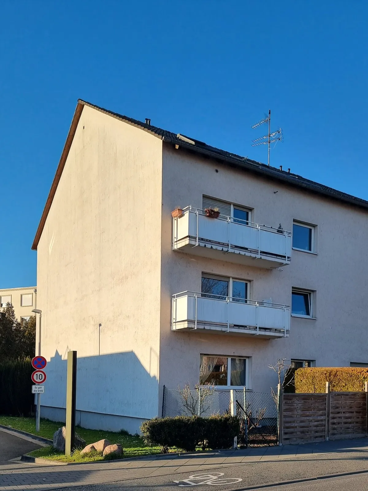Dreigeschossiges Mehrfamilienhaus mit Balkonen an einer ruhigen Straße