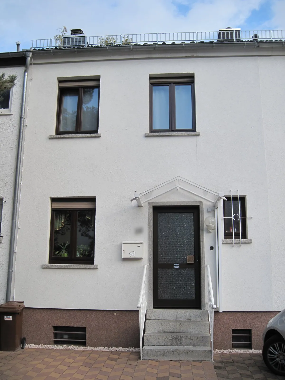 Reihenmittelhaus mit heller Fassade, Steintreppe und Vordach über der Haustür