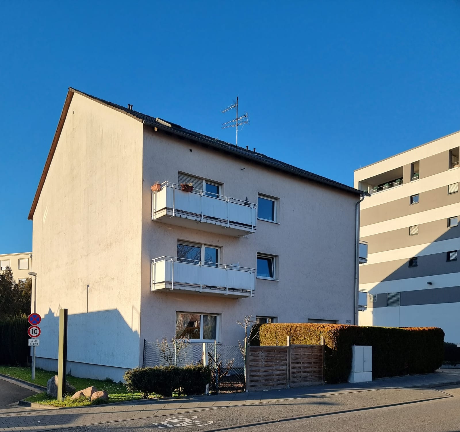 Dreigeschossiges Mehrfamilienhaus mit Balkonen an einer ruhigen Straße