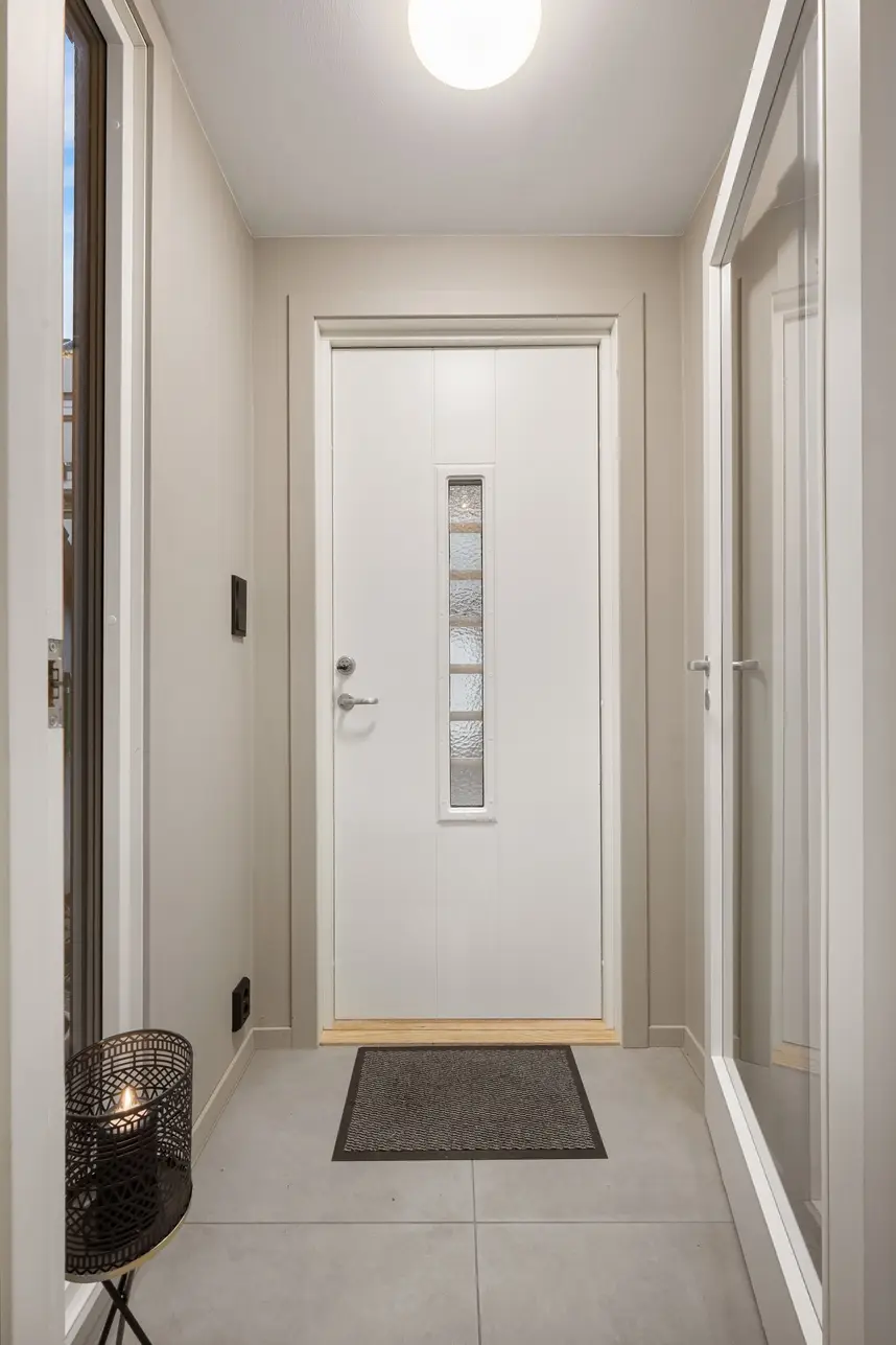 Heller Flur einer modernen Wohnung mit weißer Eingangstür und Fußmatte