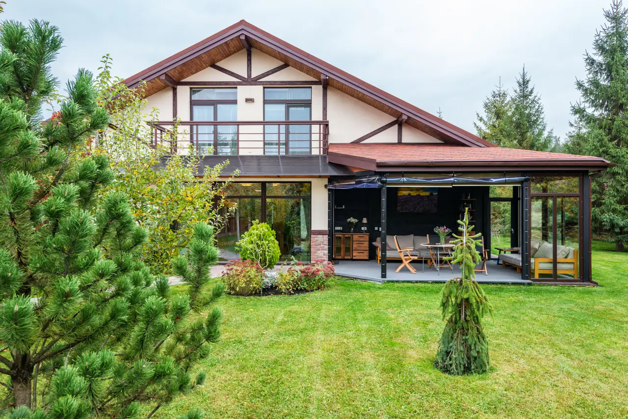 Einfamilienhaus mit Holzgiebel, Terrasse und Rasen zwischen Kiefern